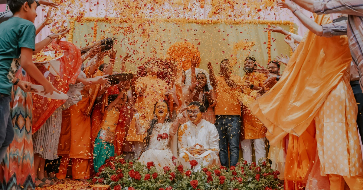 Joyful Indian wedding couple being showered with flower petals during a haldi or mehndi ceremony in Goa.
